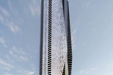 Tall, curved glass skyscraper with a diamond-pattern facade beside a sandy beach and palm trees, overlooking the ocean.