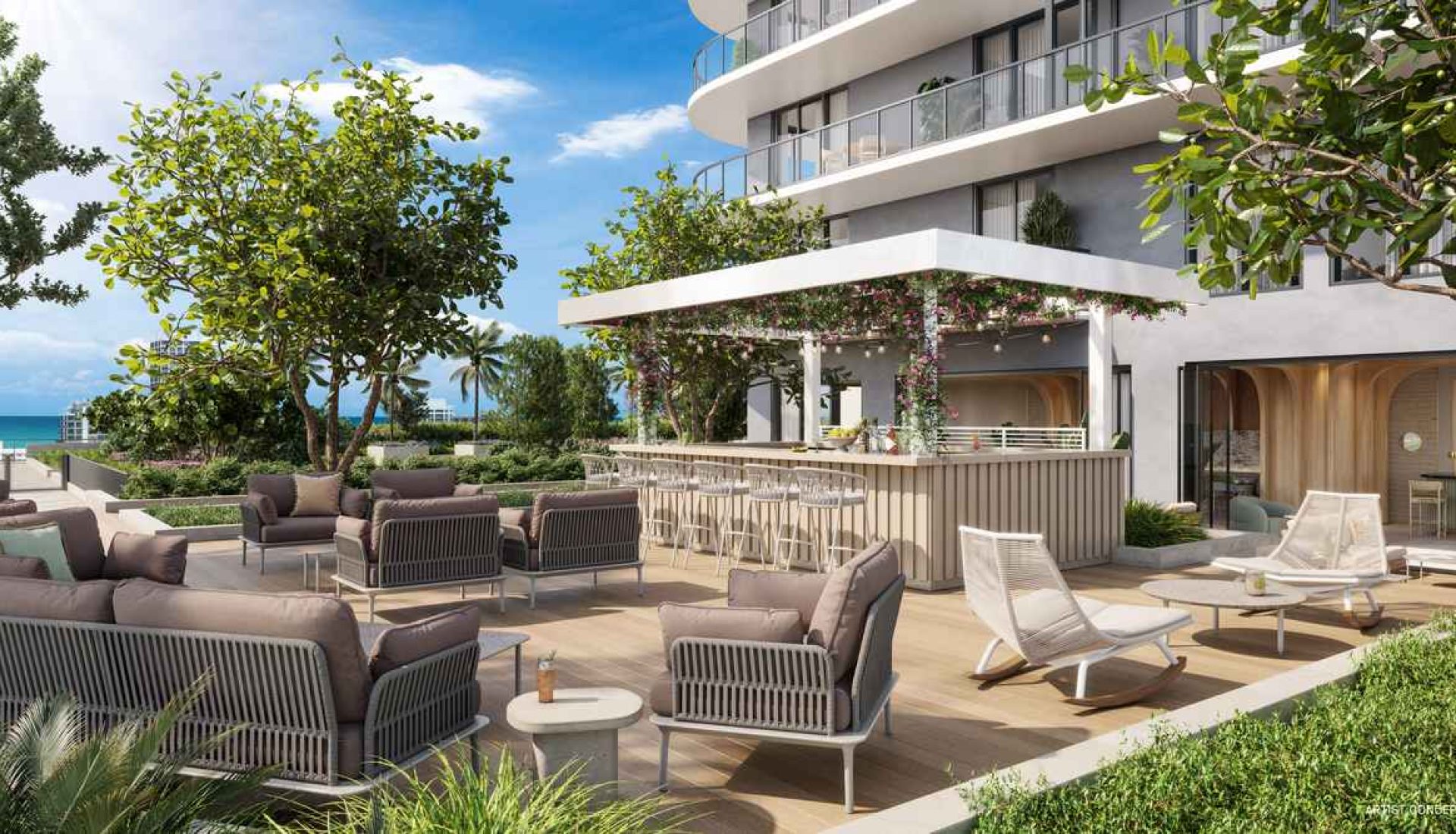 Luxurious outdoor hotel lounge with cream seating, a bar, and a view of the ocean and palm trees under a blue sky at max sun.