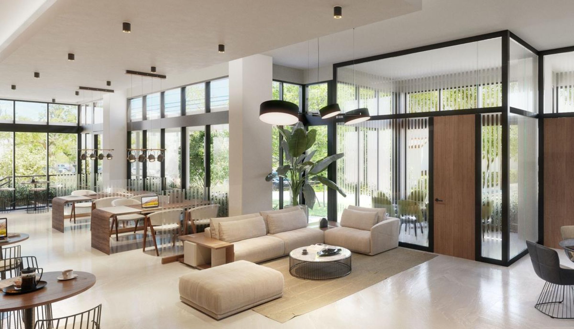 Bright modern hotel lobby with beige sofas, low coffee tables, and a large glass wall overlooking greenery outside.