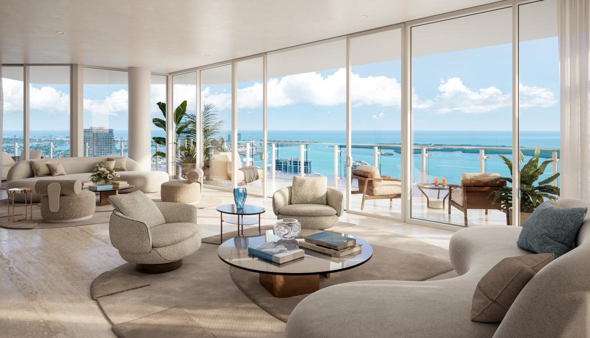 Luxurious open living room with cream seating and glass coffee table, overlooking the ocean through large windows.
