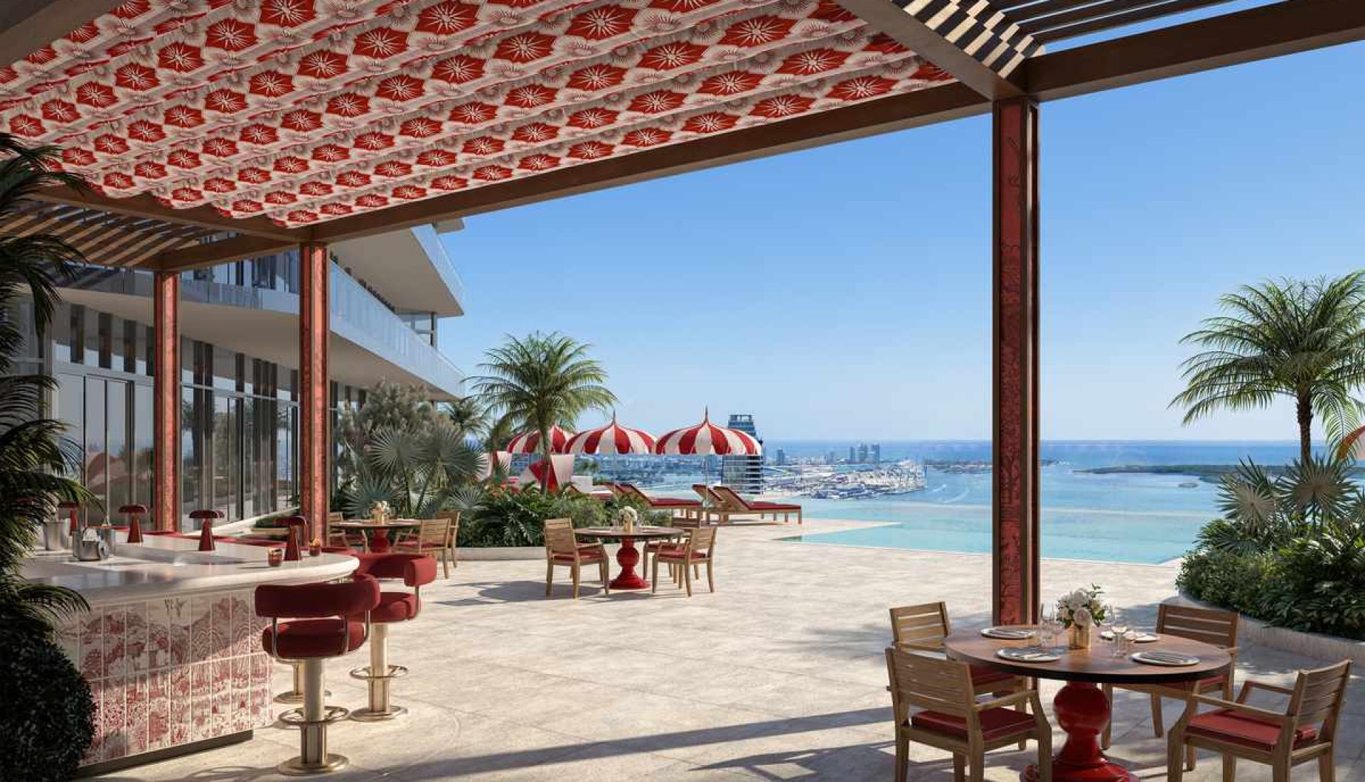 Outdoor seaside restaurant terrace with red accents, palm trees, and poolside seating overlooking the ocean marina.