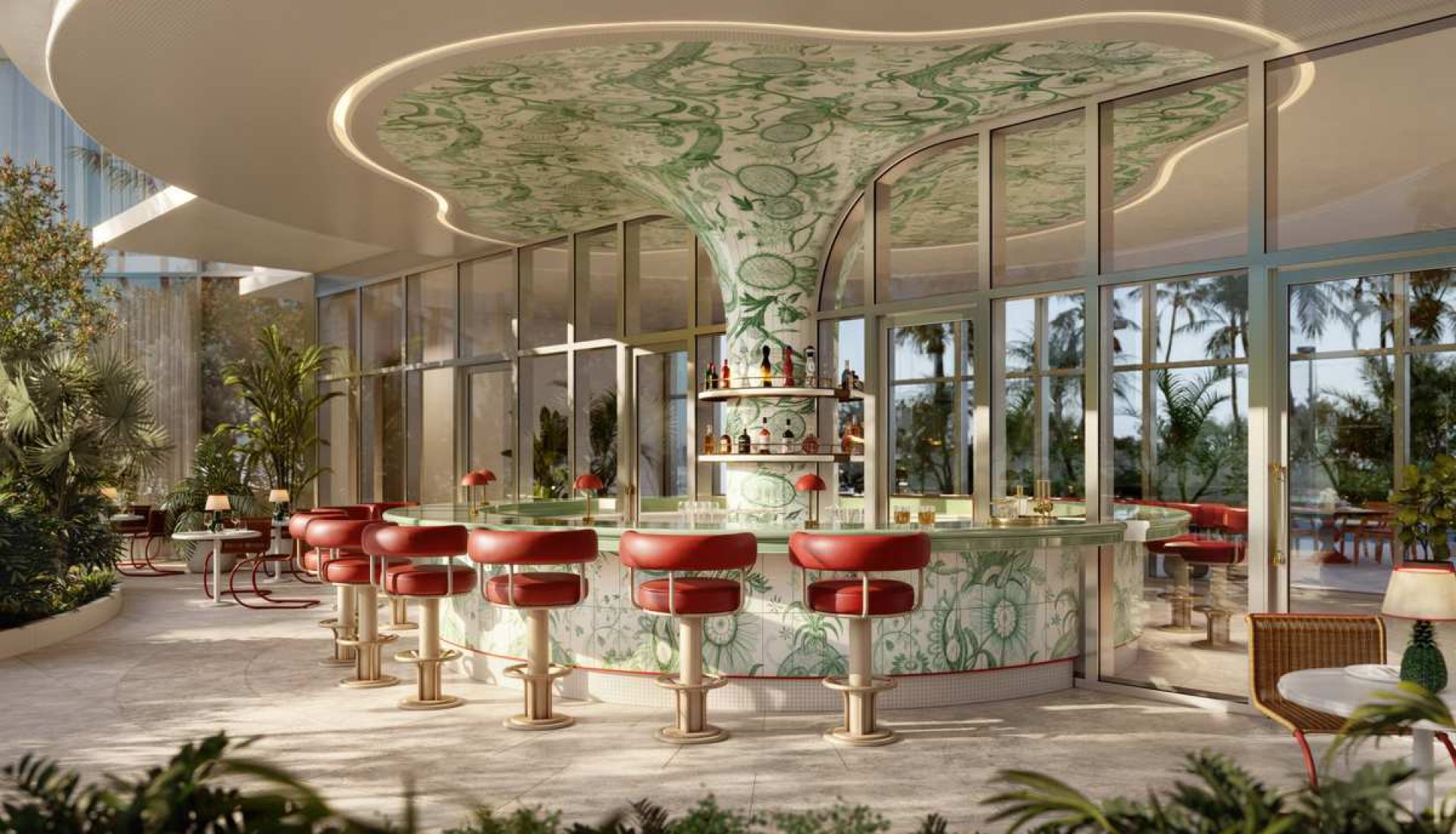 A retro-style hotel bar with red bar stools around a curved glass counter set in a sunlit tropical lounge.
