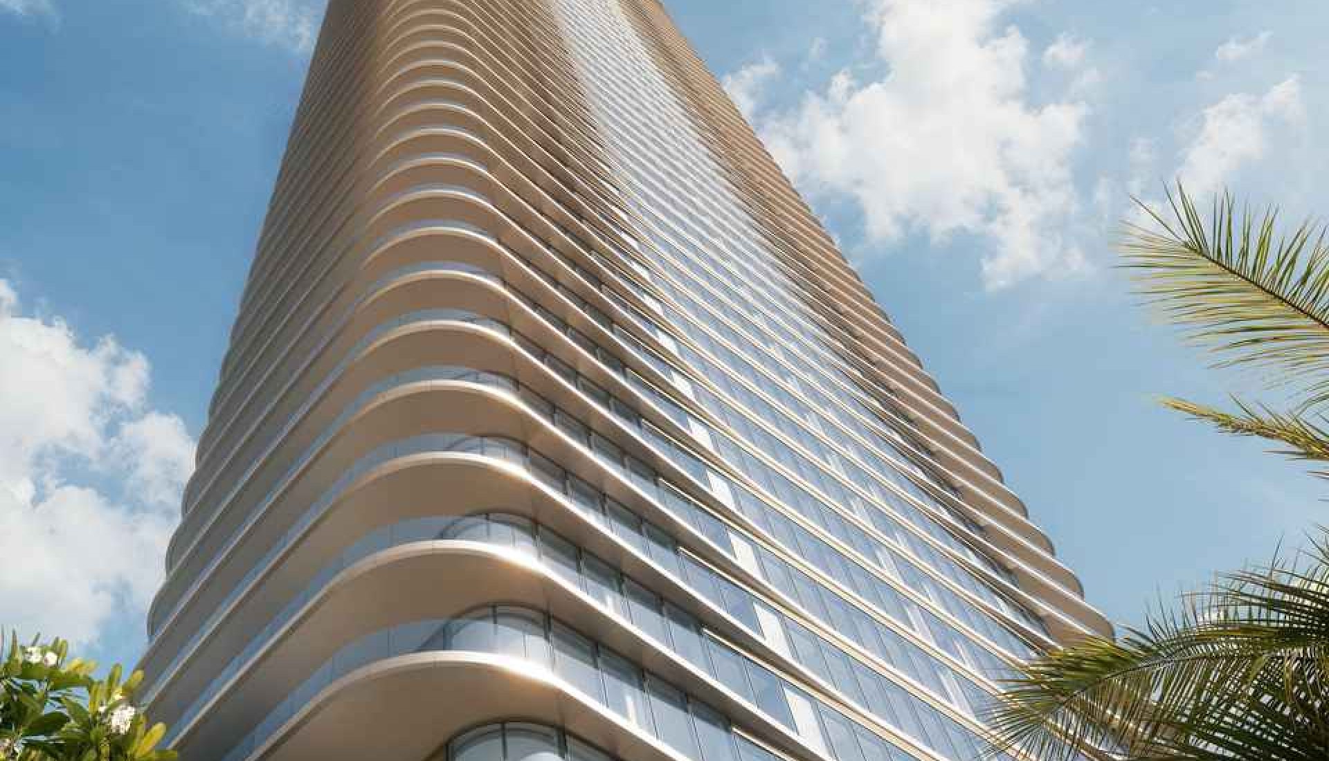 Tall glass residential tower with curved balconies reaching toward the sky, palm trees in the foreground.
