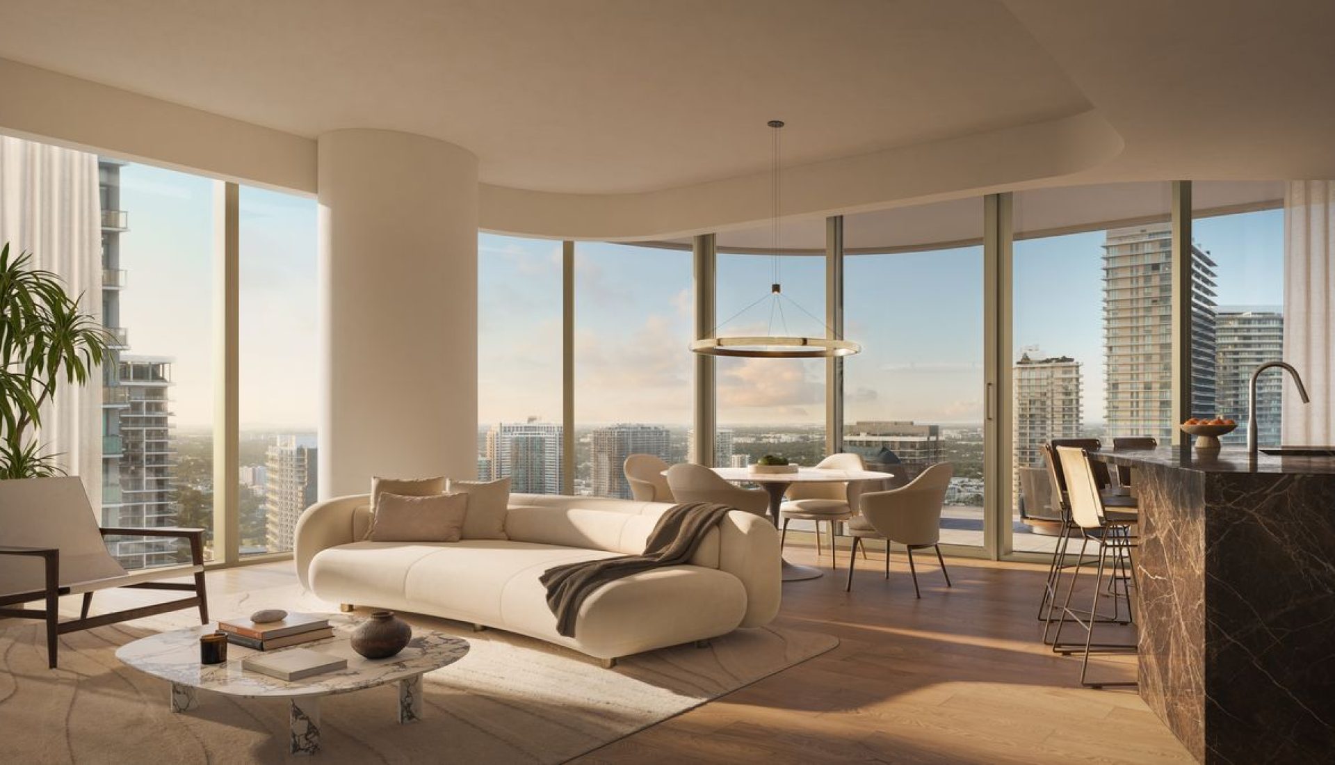 Spacious modern living room with a curved beige sofa, round marble coffee table, and floor-to-ceiling windows overlooking a city skyline.