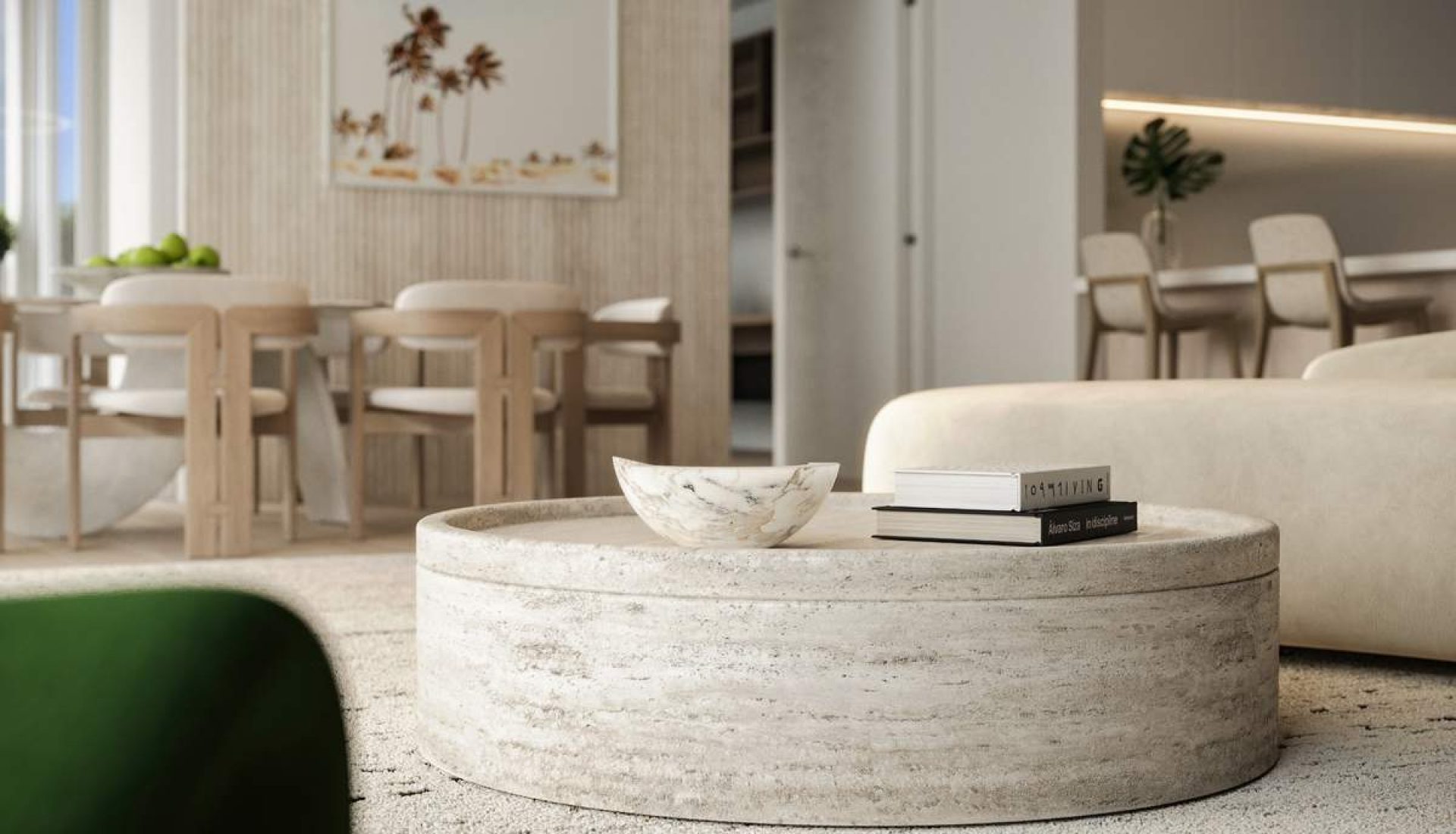 Modern living room with a round concrete coffee table, marble bowl, and a stack of books in the foreground.
