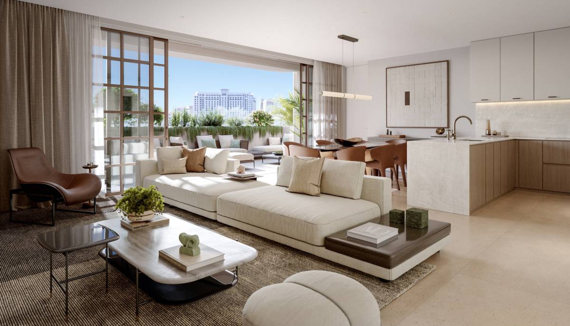 Open-plan living area with a white sectional sofa, marble coffee table, and a kitchen island; large glass doors open to a balcony with outdoor seating and city view.