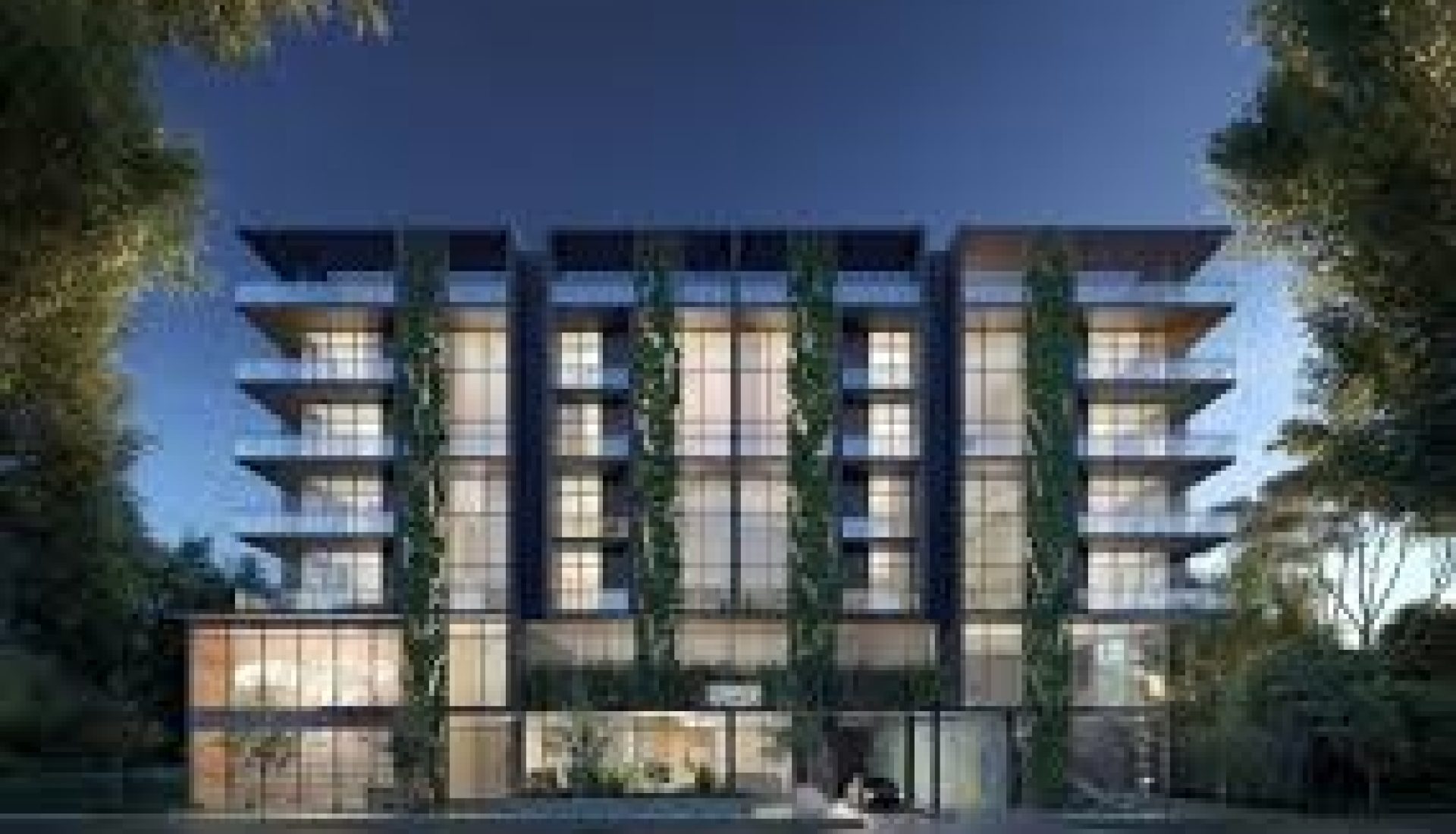 Modern multi-story glass-front residential building with balconies and surrounding trees at dusk.