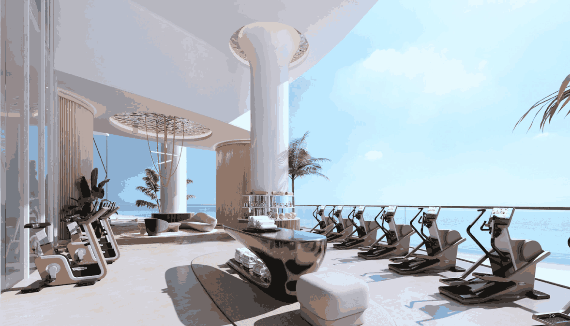 Luxurious rooftop gym with treadmills and exercise bikes facing a blue ocean view under a sunny sky