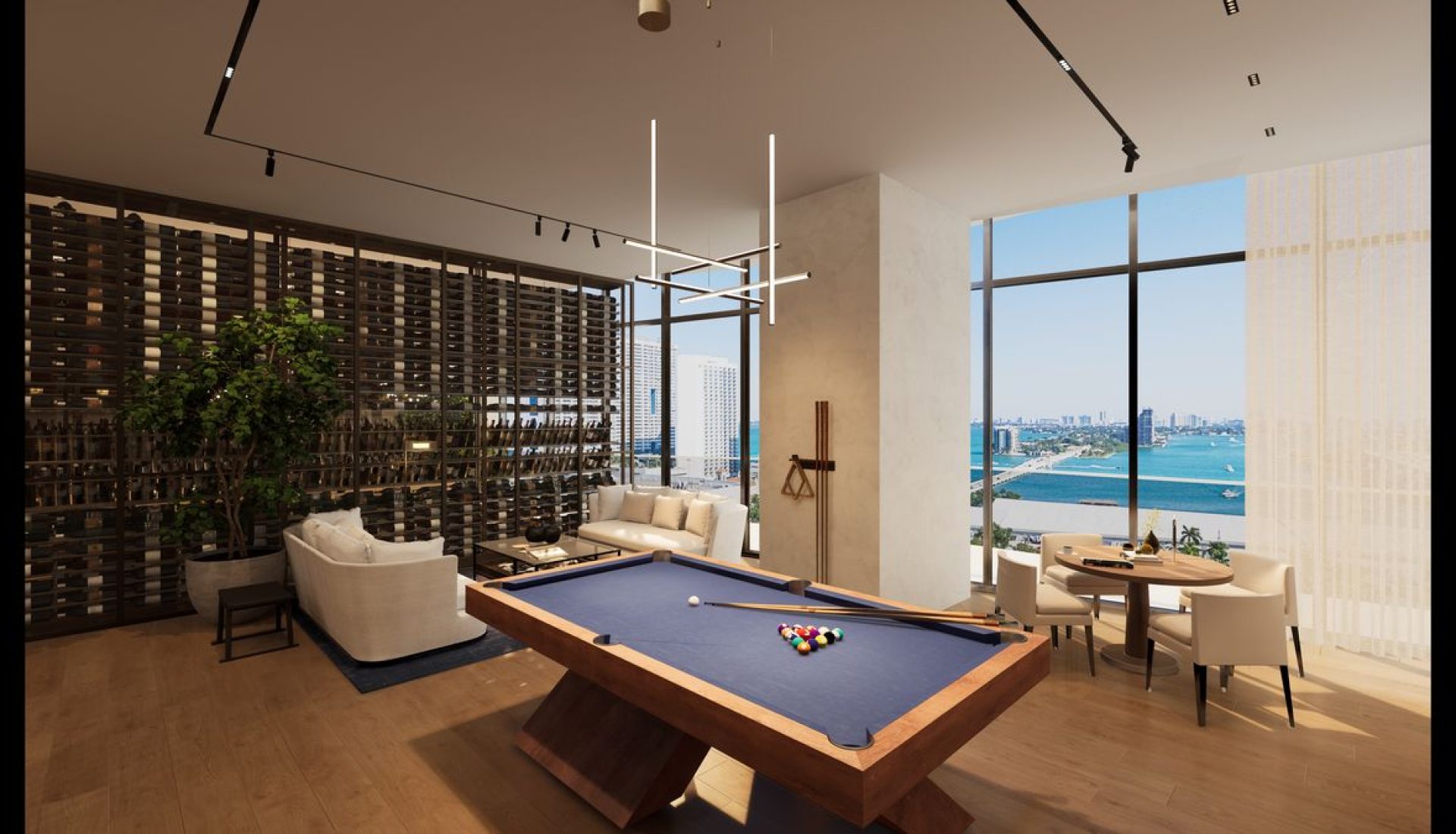 Luxurious living area with a blue billiards table, beige sofas, and a wine rack wall by large windows overlooking a harbor cityscape.