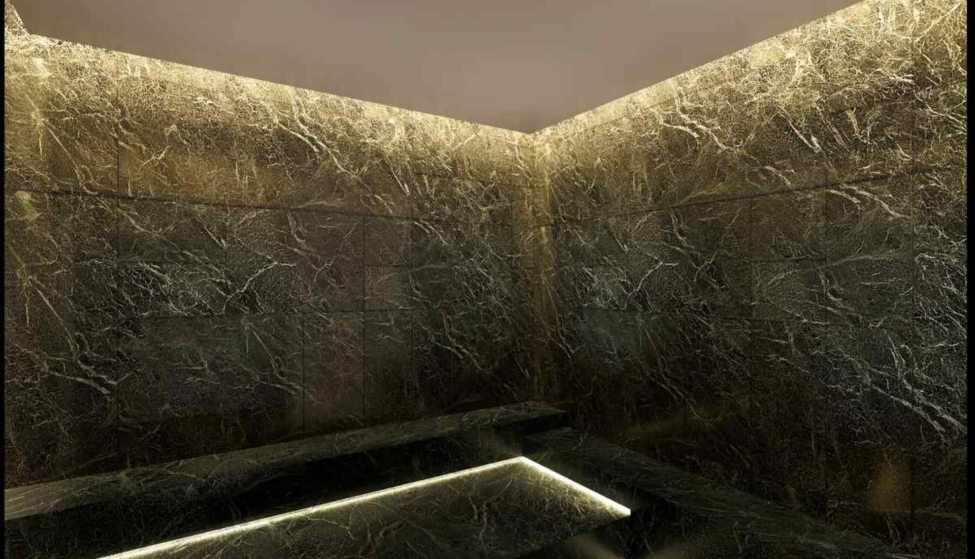 Dark marble walls and stepped platform in a dim, spa-like interior with warm LED edge lighting along the steps.