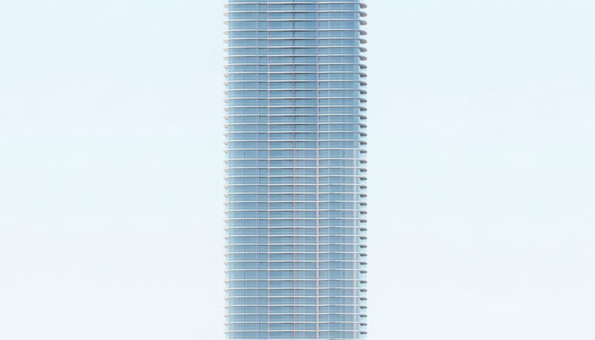 Tall glass skyscraper with a stepped, crown-like top rising from a rounded base building with palm trees at the plaza.
