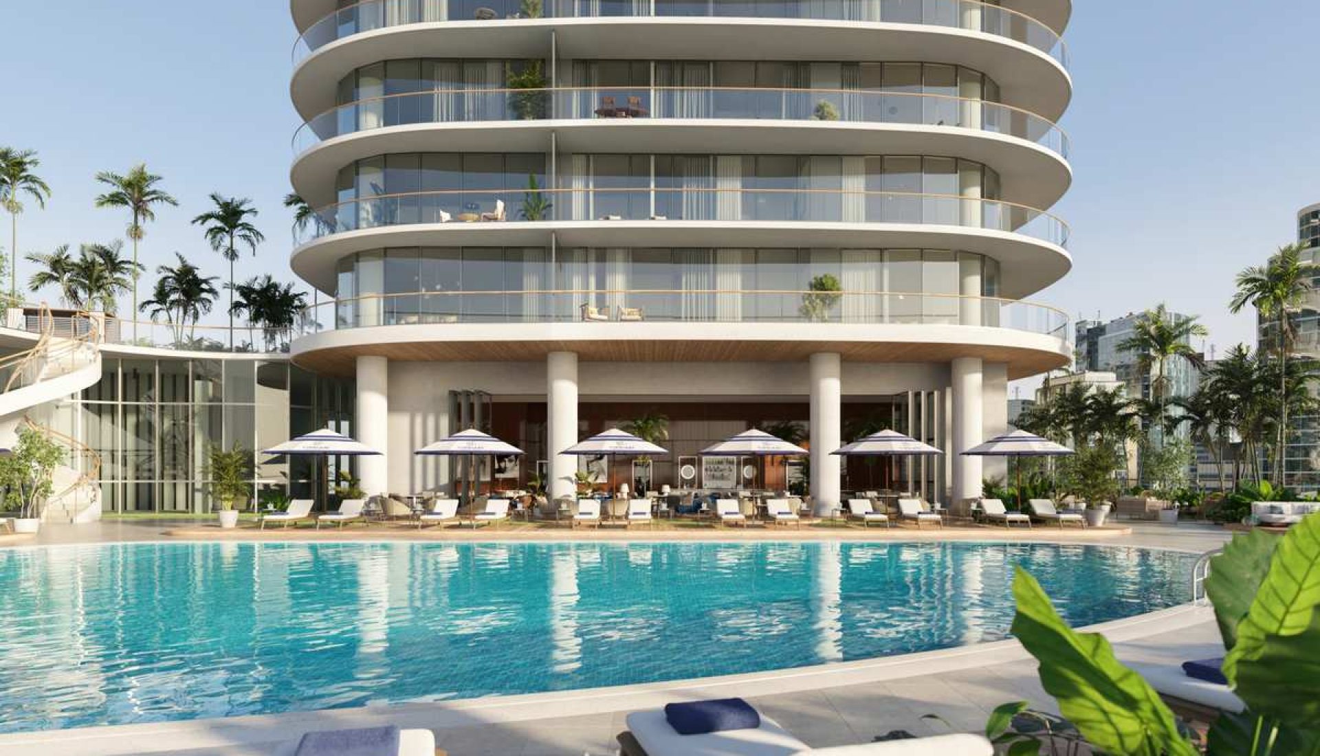 Luxurious hotel pool area with white lounge chairs and umbrellas in front of a curved glass-fronted building.