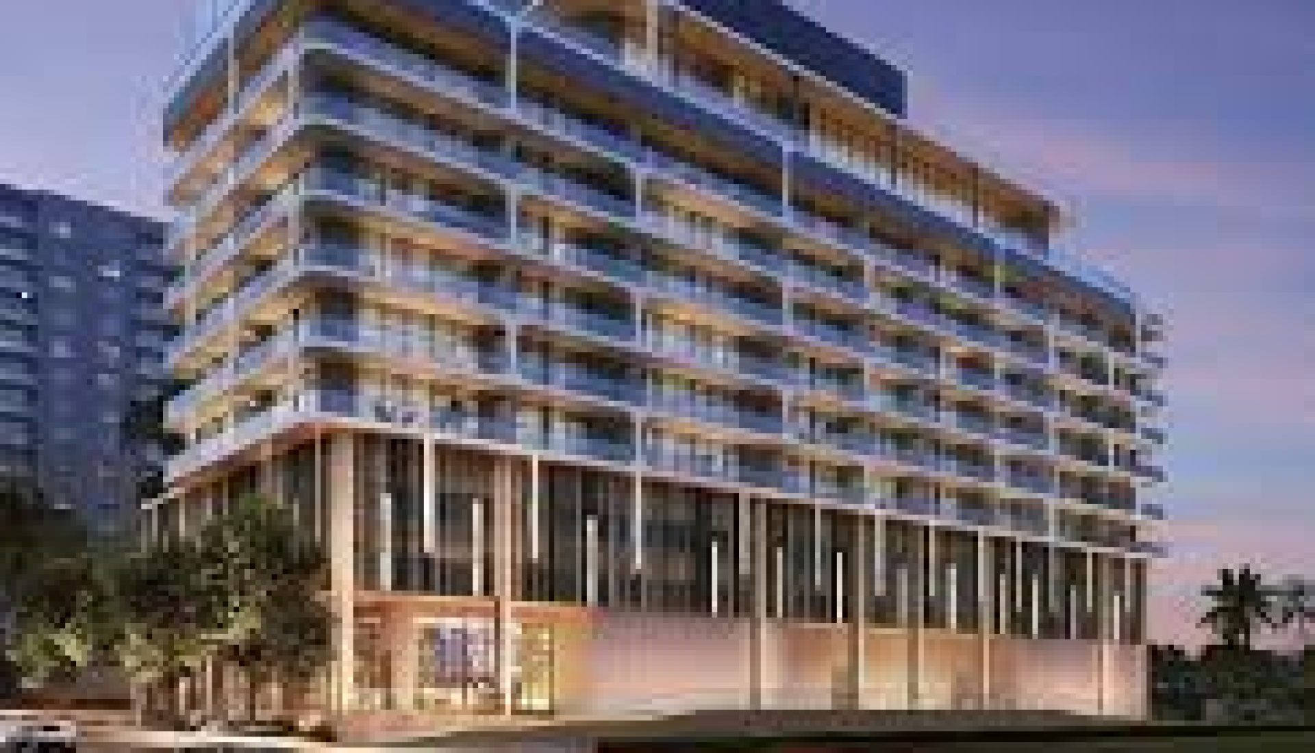 Modern, multi-story building with curved balconies at dusk, large glass ground-floor storefronts, and palm trees nearby.
